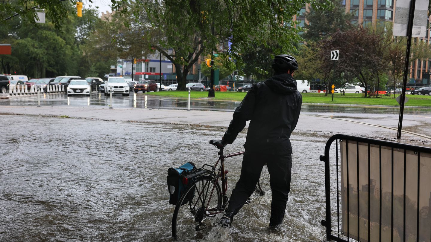 A person walks their bike along a flooded road at the Southwest entrance of Prospect Park amid a coastal storm on Friday, Sept. 29, 2023, in the Flatbush neighborhood of Brooklyn in New York City.