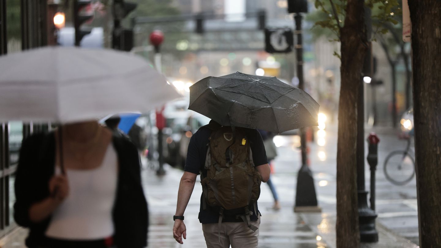 People walk in light rain on Stuart Street in Boston.